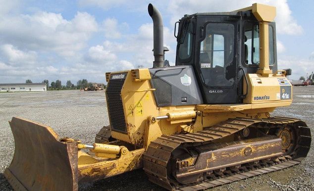 A yellow bulldozer is parked in a gravel lot.