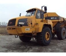A yellow dump truck is parked in a dirt lot.