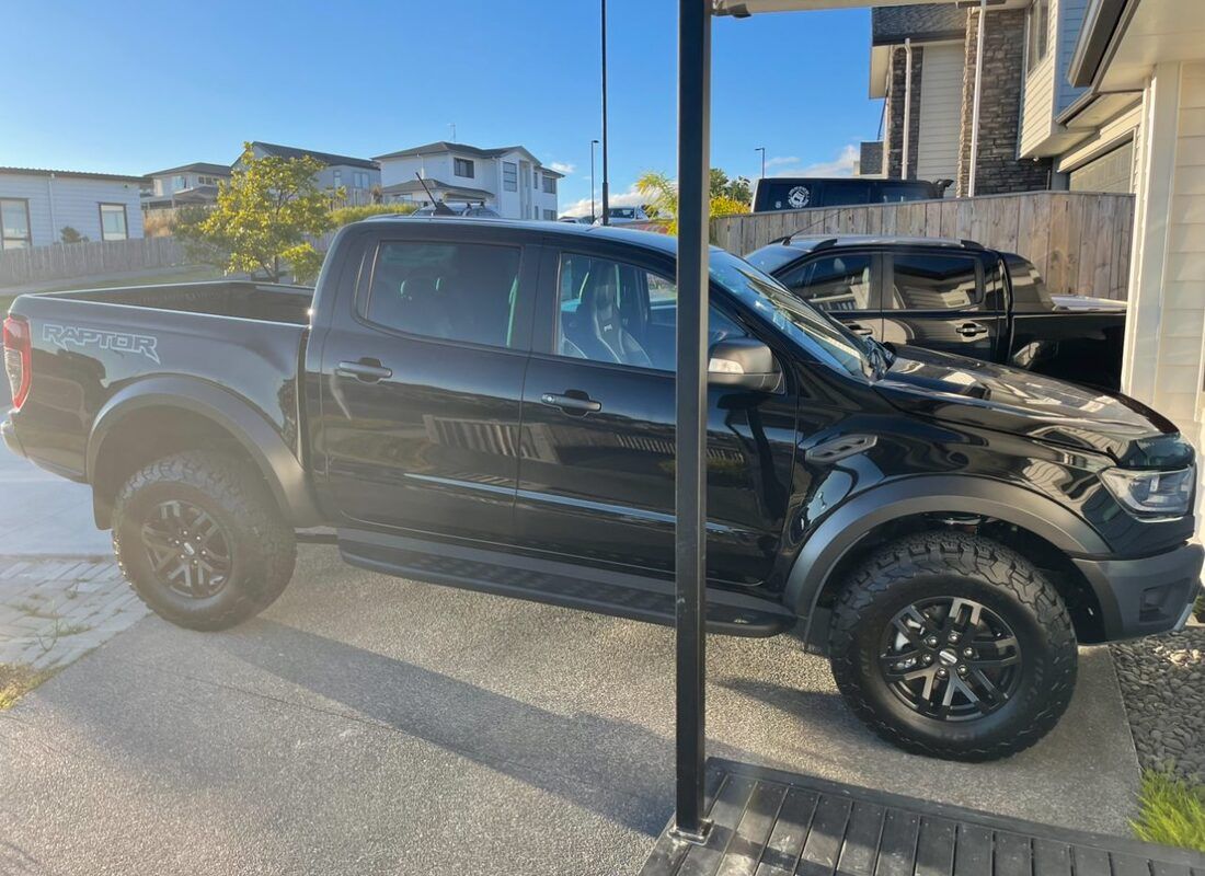 A black pickup truck is parked in front of a house.
