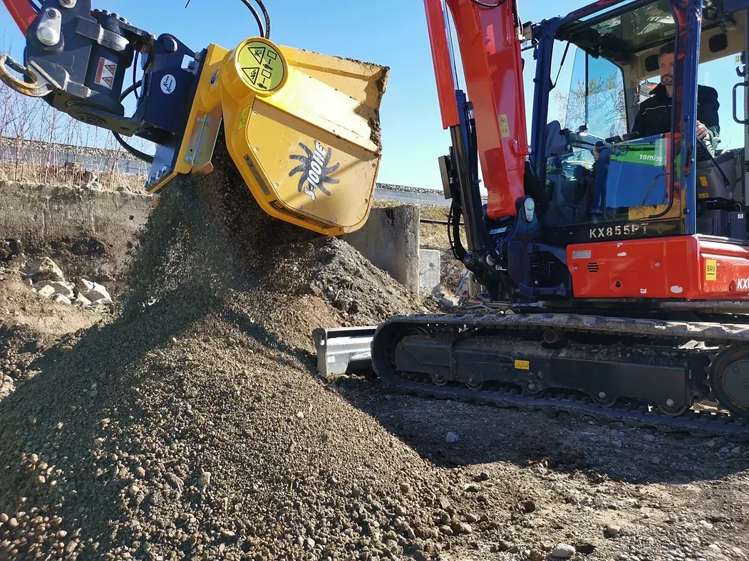 A red and yellow excavator is loading dirt into a yellow bucket.