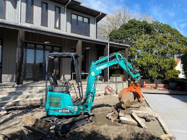 A small excavator is parked in front of a house.