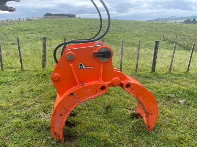 A large orange machine is sitting in the middle of a grassy field.