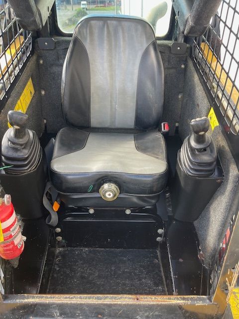 The inside of a skid steer with a seat and controls.