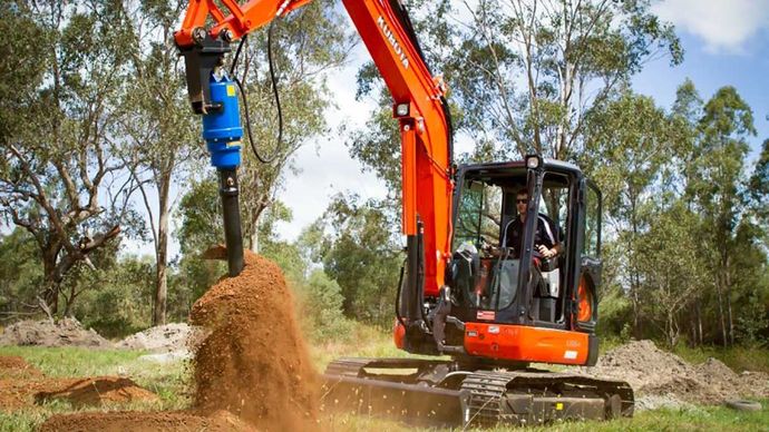 An excavator is digging a hole in the ground in a field.