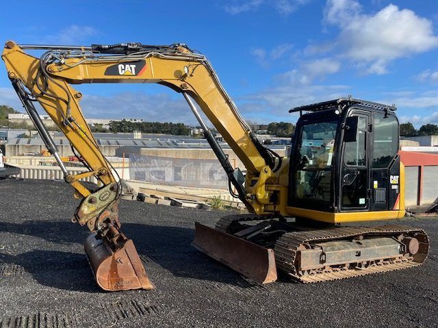 A yellow cat excavator is parked in a parking lot.