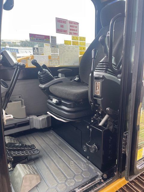 The inside of a construction vehicle with a seat and controls