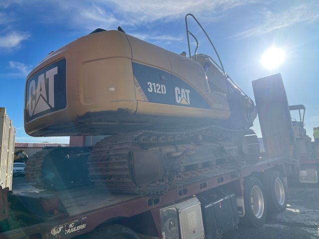 A cat excavator is sitting on top of a flatbed truck.