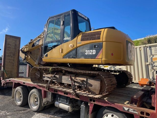 A cat excavator is sitting on top of a flatbed truck.