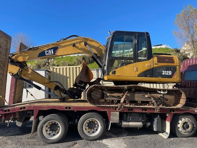 A cat excavator is sitting on top of a flatbed truck.