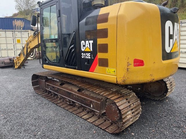 A yellow and black cat excavator is parked in a gravel lot.