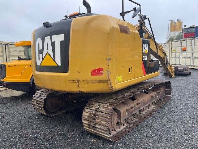 A yellow cat excavator is parked in a gravel lot.
