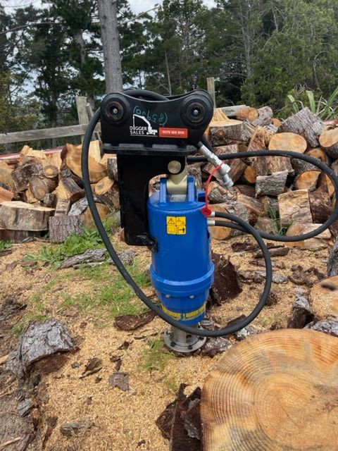 A blue drill is sitting on top of a pile of logs.