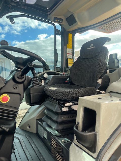The inside of a tractor with a black seat and steering wheel
