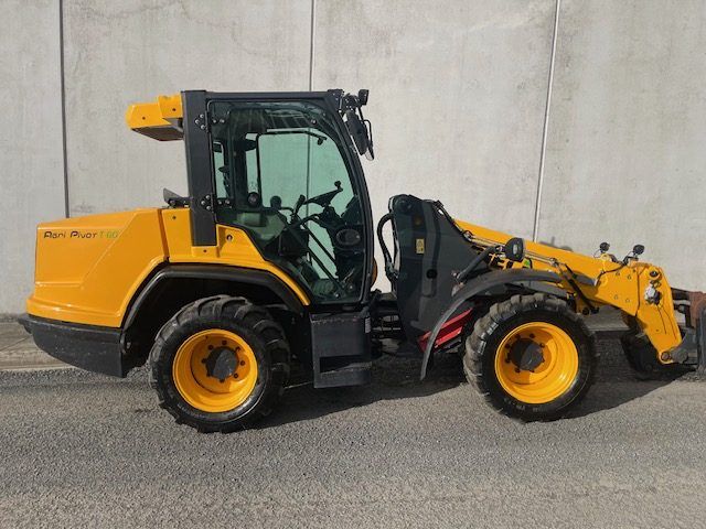 A yellow tractor is parked in front of a concrete wall