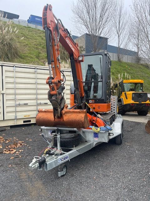 An excavator is sitting on a trailer in a parking lot.