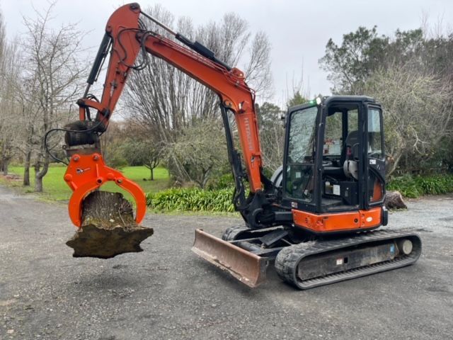 A small orange excavator is digging a hole in the ground.