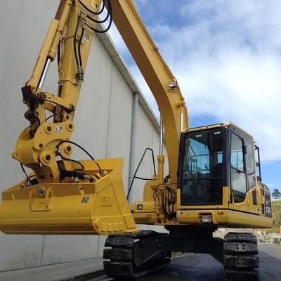 A large yellow excavator is parked in front of a building