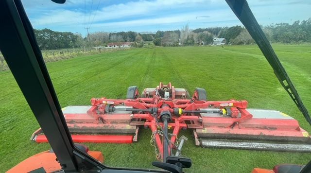 A tractor is cutting grass in a field.