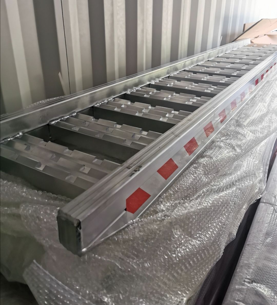 A metal ladder is sitting on top of a plastic container.