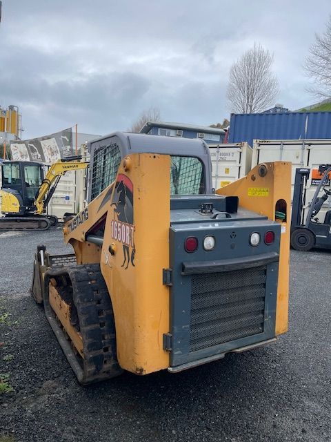 A yellow skid steer is parked in a parking lot
