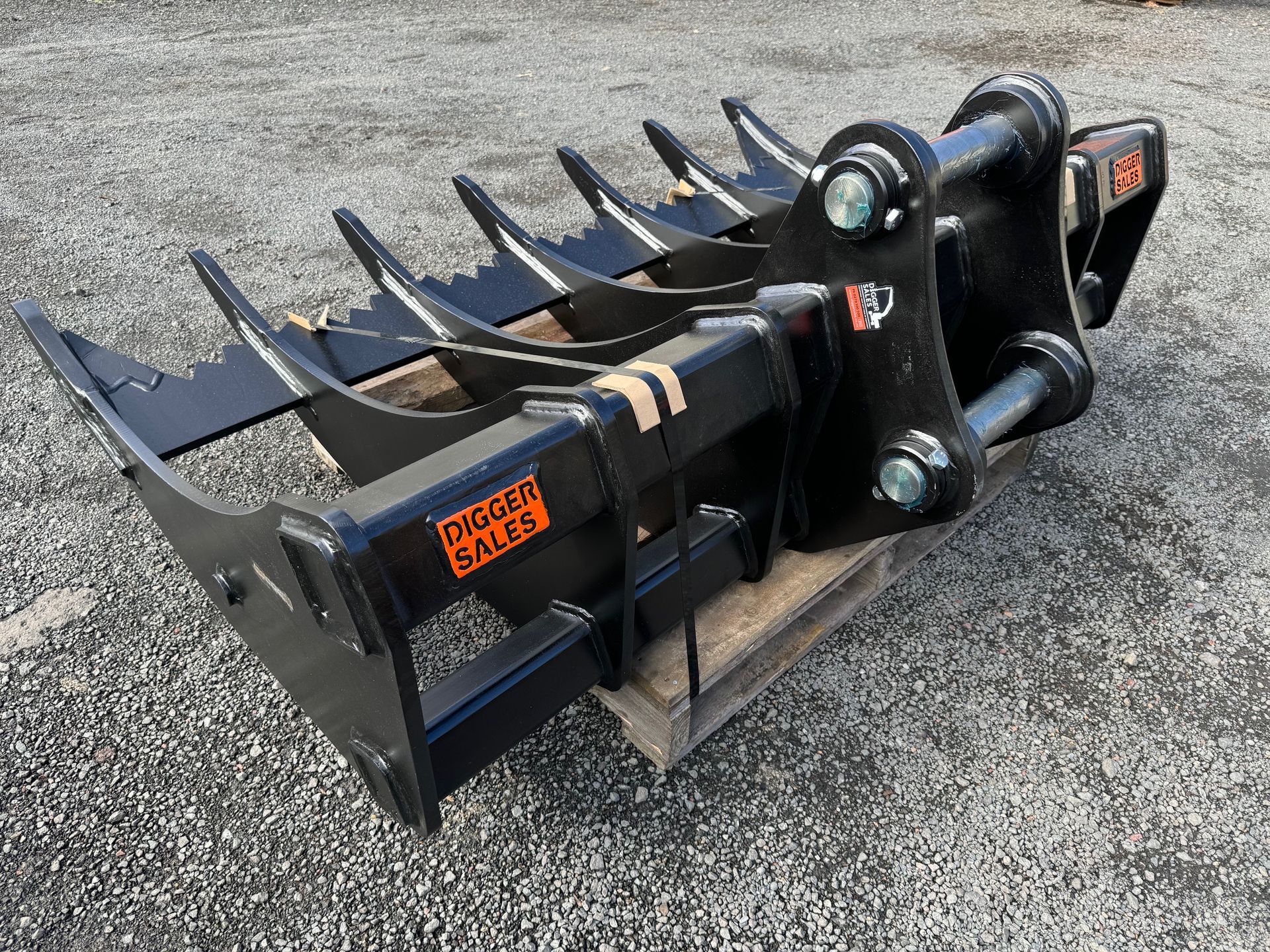 A black rake is sitting on top of a wooden pallet on the ground.