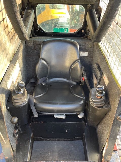 The inside of a tractor with a black seat and controls.