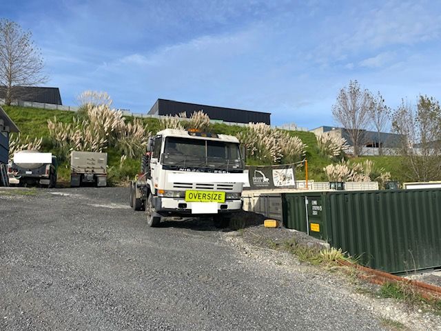 A white truck with a yellow license plate is parked on the side of the road.