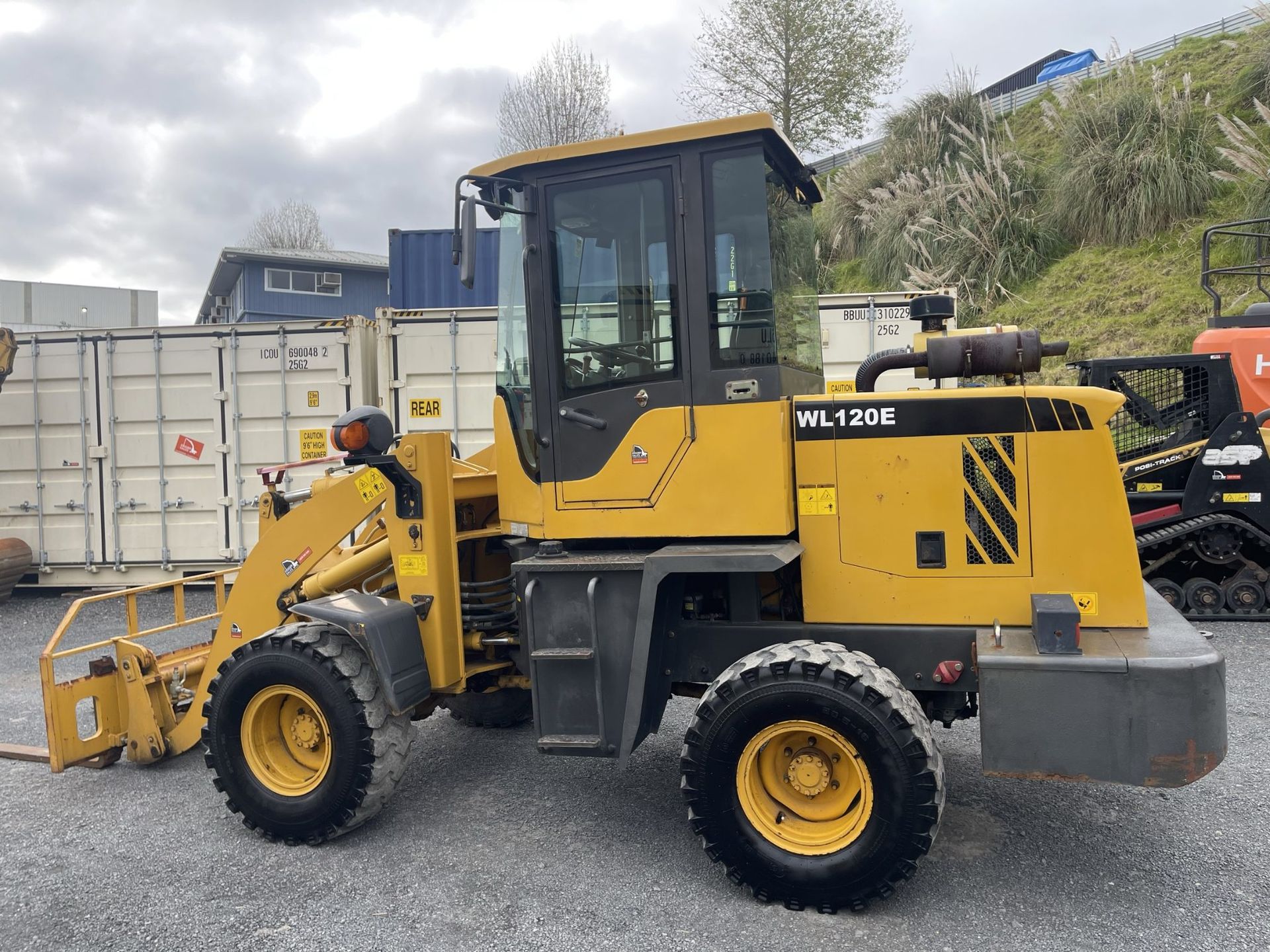 A yellow and black wheel loader is parked in a gravel lot.