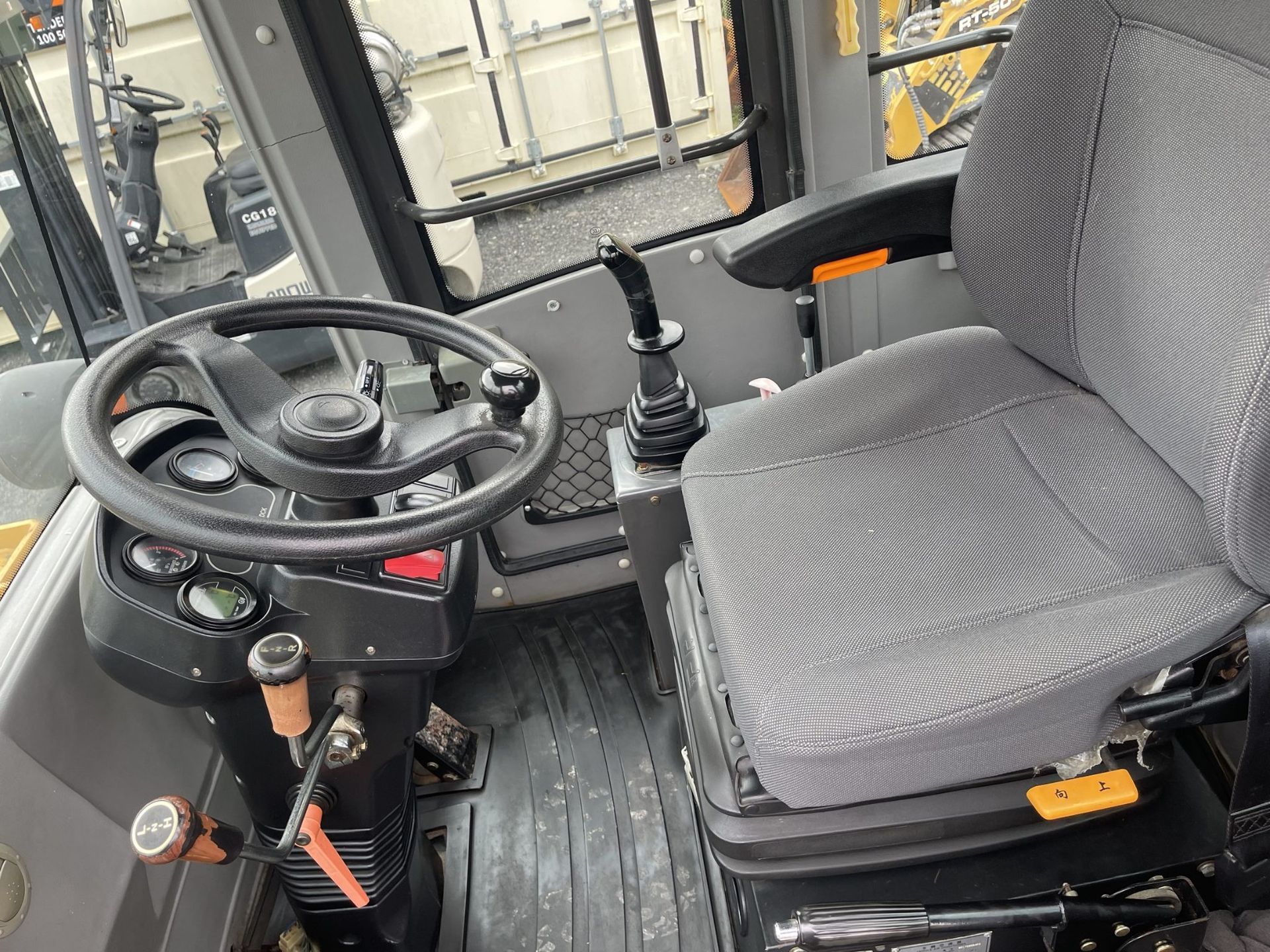 The inside of a tractor with a steering wheel and seat.
