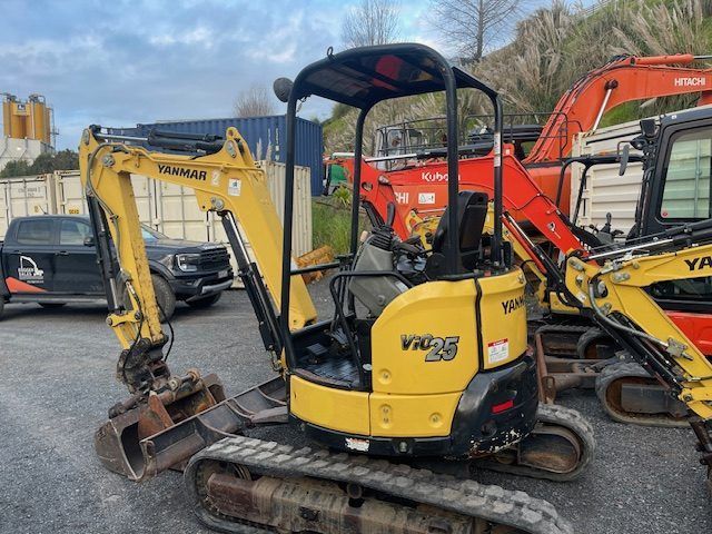 A small yellow excavator is parked in a parking lot.