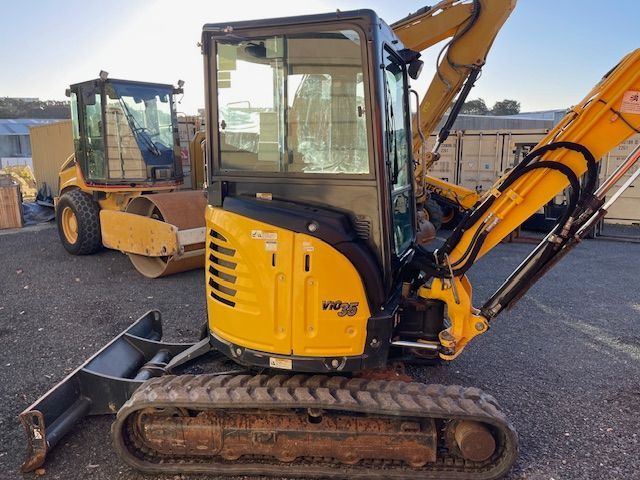 A small yellow excavator is parked in a parking lot