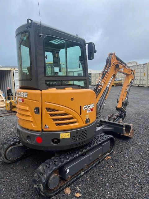A case excavator is parked in a gravel lot.