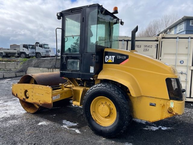 A yellow cat roller is parked in a parking lot