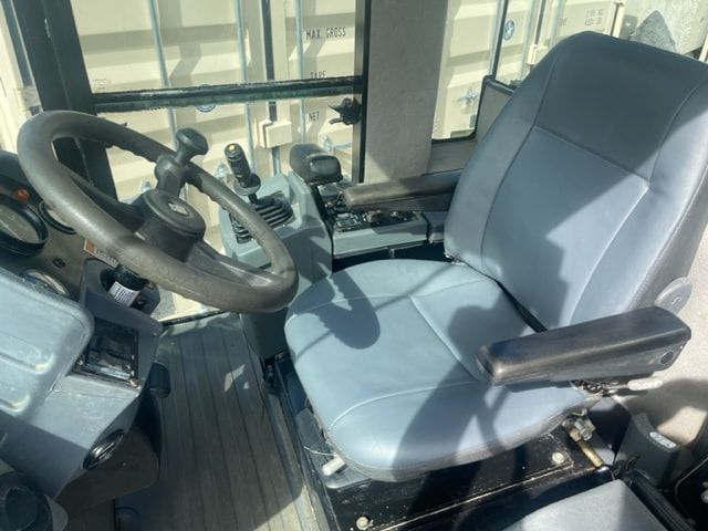 The inside of a tractor with a blue seat and steering wheel