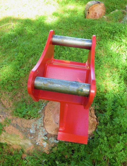 A red object is sitting on top of a stump in the grass.