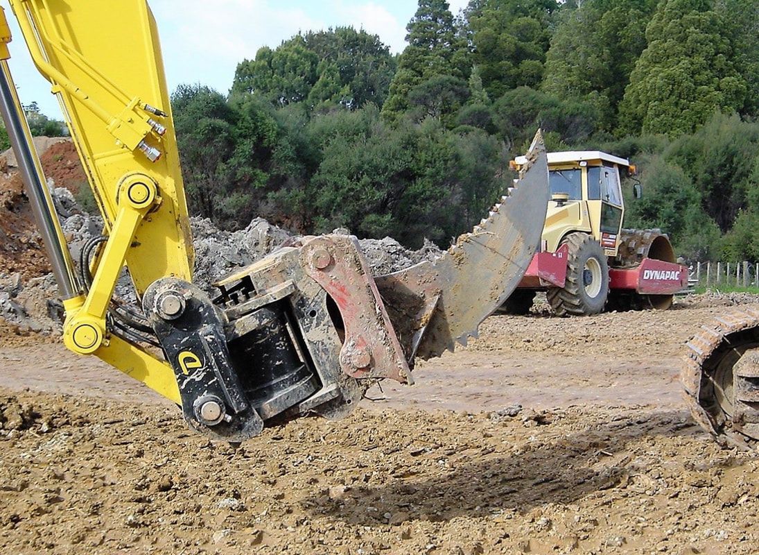A yellow excavator is moving dirt in a field.