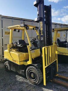 A yellow forklift is parked in front of a shipping container.