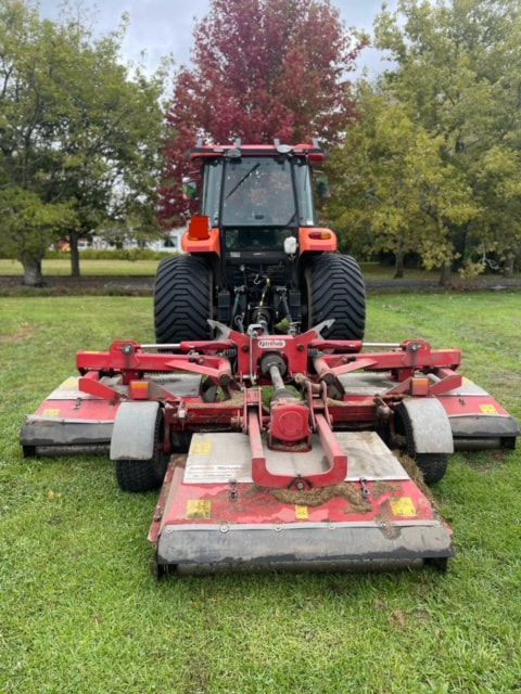 A red tractor is parked in a grassy field.