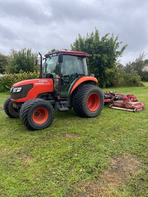 A red and black tractor is parked in a grassy field.