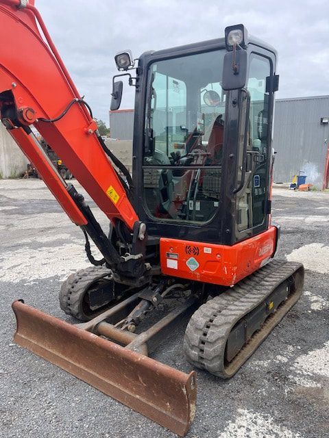 A small red excavator is parked in a parking lot