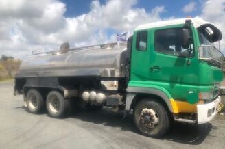 A green and yellow truck is parked in a parking lot.