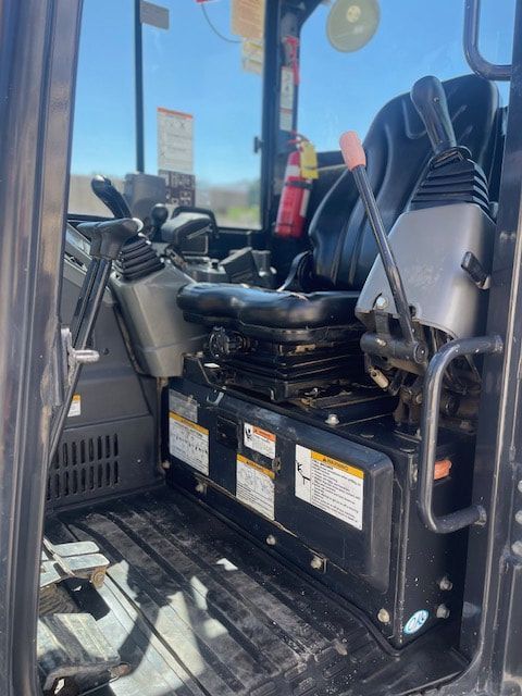 The inside of a construction vehicle with a fire extinguisher on the floor.
