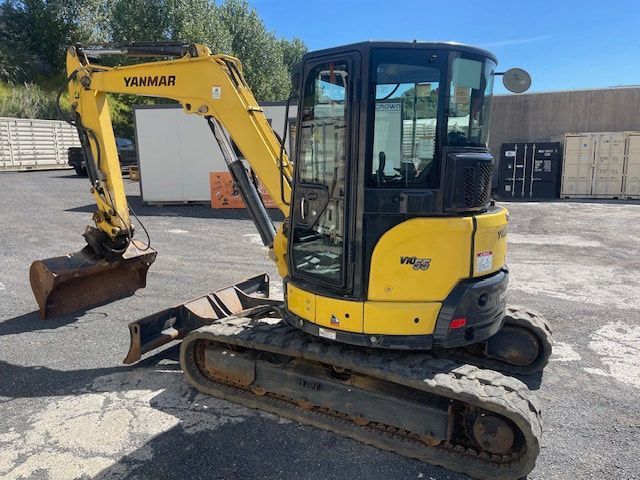 A yellow yanmar excavator is parked in a parking lot.