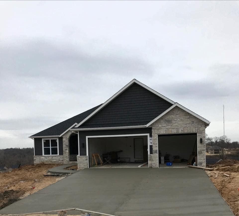 New house with a two-car garage and freshly poured concrete driveway under a cloudy sky