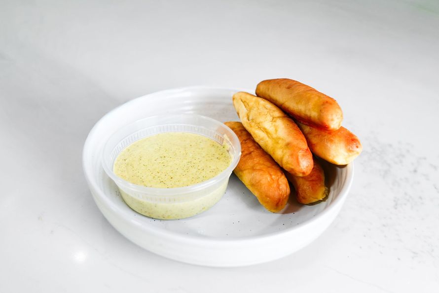 Plate of fried spring rolls with a small bowl of dipping sauce on a white background