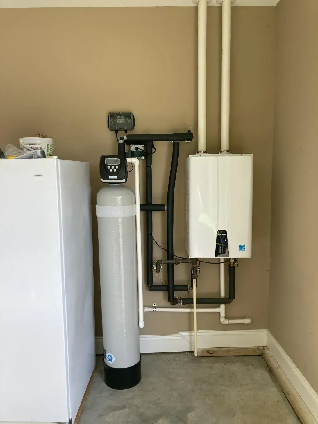 A laundry room with a washer and dryer and a water filter