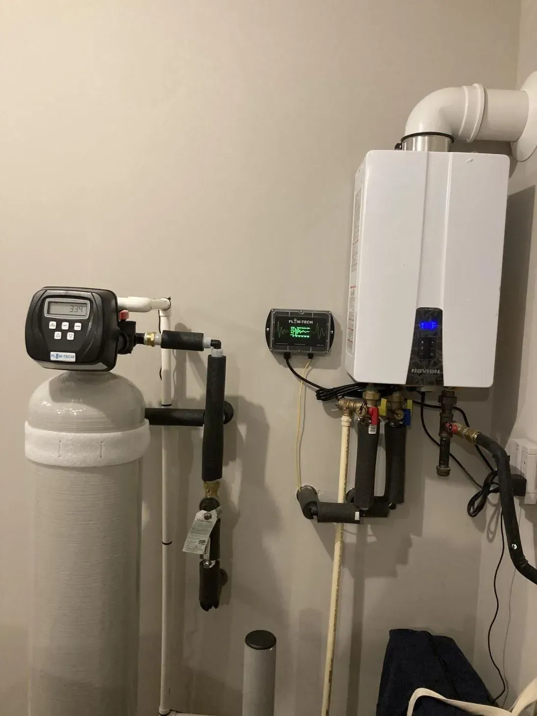 A room with a water filter and a boiler on the wall.