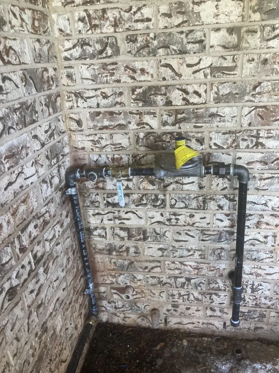 A pipe is connected to a brick wall in a room.