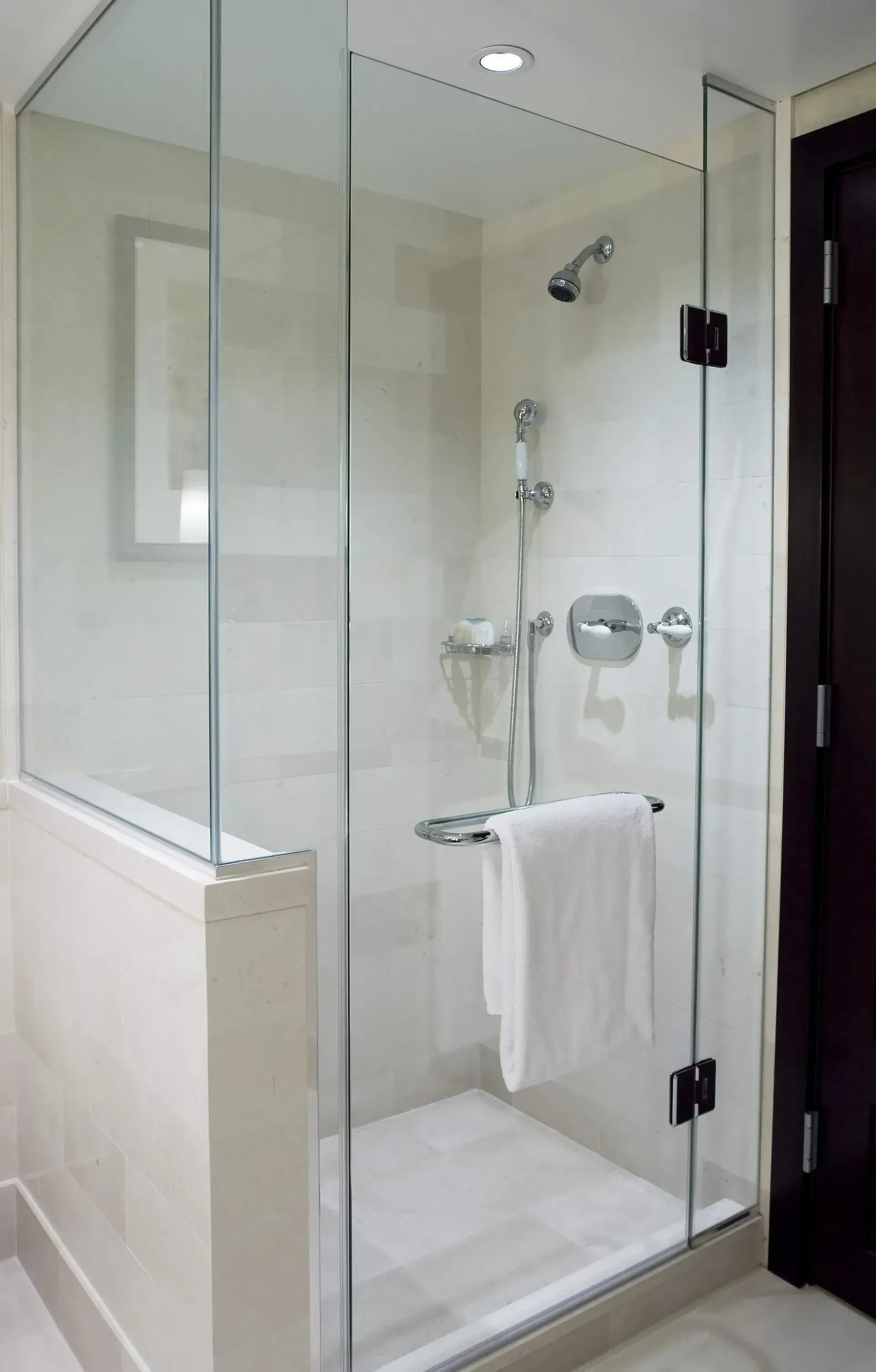 A bathroom with a walk in shower with a glass door