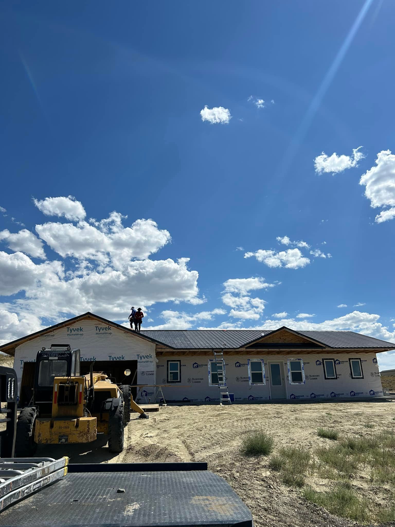 A house under construction with a bulldozer parked in front of it.